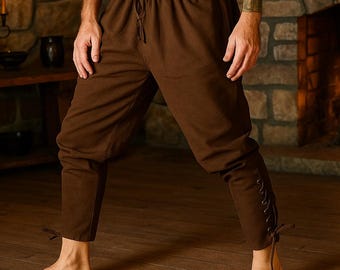 May include: Brown medieval-style pants with a drawstring waist and lace-up details on the lower legs. The pants are made of a soft fabric and are suitable for historical reenactments or themed events.