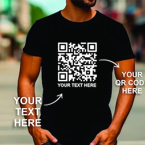 Może przedstawiać: Czarny T-shirt z białym wzorem kodu QR. Tekst "YOUR TEXT HERE" jest nadrukowany pod kodem QR. Tekst "YOUR QR CODE HERE" jest nadrukowany po prawej stronie koszulki. Tekst "YOUR TEXT HERE" jest nadrukowany po lewej stronie koszulki.
