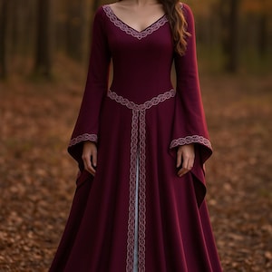 May include: A deep burgundy medieval gown with long, flared sleeves and a V-neck. The dress has detailed embroidered trim on the neckline, waist, and sleeves. The floor-length dress has a flowing skirt, ideal for historical events or themed occasions.