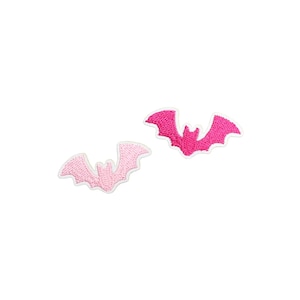 May include: Two embroidered bat patches. One is light pink with a white border, and the other is hot pink with a white border. The patches are on a white background.