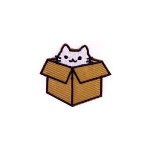 May include: Embroidered patch featuring a white cat peeking out of a brown cardboard box. The cat has black eyes and whiskers. The box has a textured appearance with a black outline. This patch is ideal for adding to clothing or accessories.