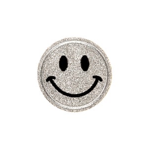 May include: A round, silver glitter smiley face patch with a black smile and two black oval eyes. The patch is circular and has a textured appearance, perfect for adding to clothing or accessories.