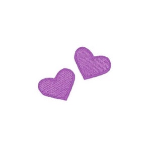 May include: Two embroidered purple heart patches on a white background. Each heart has a stitched texture and a darker purple border. The hearts are slightly different sizes and positioned at an angle.