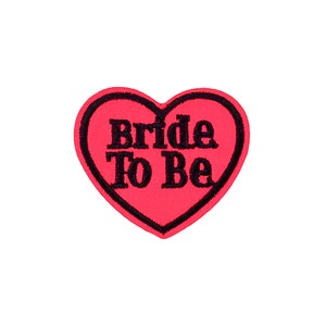 May include: A red heart-shaped patch with black embroidery that reads "Bride To Be".