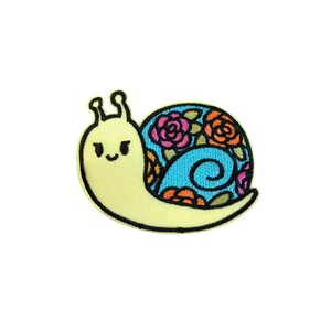 Könnte beinhalten: Eine gestickte gelbe Schnecke mit einem blauen, orangefarbenen und rosafarbenen Blumendesign auf ihrer Schale.