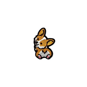 May include: Embroidered patch of a brown and white corgi with black outlines. The corgi is looking to the left and has its tongue sticking out.