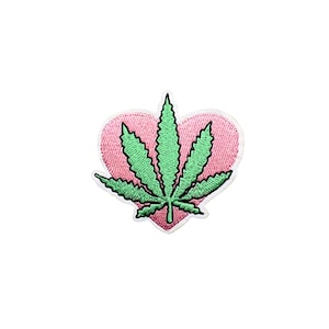 May include: Green marijuana leaf inside a pink heart.  The heart is outlined in white.