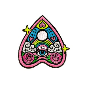 May include: Pink heart-shaped embroidered patch with a rainbow, clouds, an eye, and roses. The patch has a yellow star on each side.