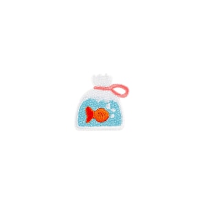 Könnte beinhalten: Gestickter Aufnäher mit einem Cartoon-Fisch in einer blauen Tüte. Der Fisch ist orange, und die Tüte hat einen weißen oberen Teil mit einer rosa Schlaufe. Der Aufnäher hat ein strukturiertes, genähtes Design.