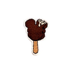 May include: A brown chocolate Mickey Mouse ice cream bar on a stick with a white background.