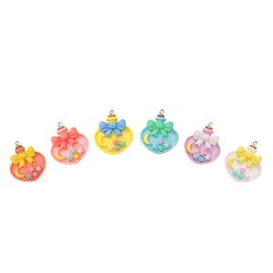 May include: Seven heart-shaped charm pendants with a crescent moon and stars design. Each charm features a different pastel color and a bow.