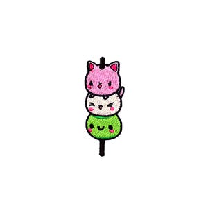 Puede incluir: Un mochi verde, blanco y rosa en un palo con caras de dibujos animados lindas.