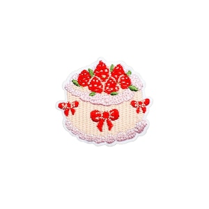 May include: Embroidered patch featuring a two-tiered cake design. The cake is decorated with red strawberries and bows. The patch has a light beige base with pink and red accents, perfect for adding to clothing or accessories.