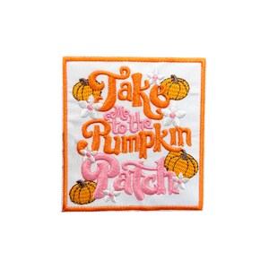Puede incluir: Parche bordado termoadhesivo con un diseño naranja y rosa. El parche dice "Take me to the Pumpkin Patch" con calabazas y flores.