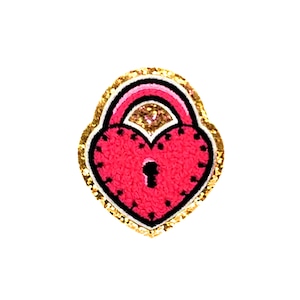 Könnte beinhalten: Ein rosafarbenes herzförmiges Vorhängeschloss mit goldener Glitzerbordüre. Das Vorhängeschloss hat ein Schlüsselloch und ist ein süßes und skurriles Design.