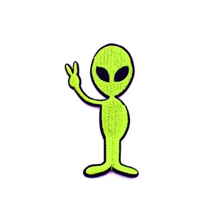Pode incluir: Patch bordado com um alienígena verde com olhos pretos e um sinal de paz.