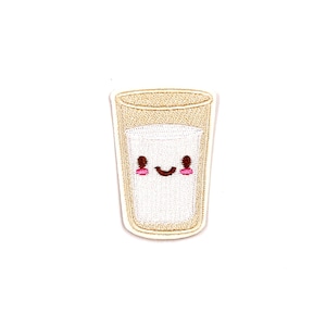 May include: A white embroidered patch of a glass of milk with a smiling face. The glass is outlined in beige thread.