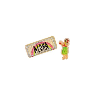 Op de afbeelding: Twee geborduurde patches: een rechthoekige met "ALOHA" over een regenboog, en een tweede patch van een hula-danseres in een groene rok en rode bloemenkroon. De patches staan op een witte achtergrond.