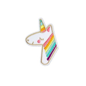 May include: Embroidered patch featuring a white unicorn head with a rainbow mane and horn. The unicorn has closed eyes and a pink blush. The patch is outlined in gold and has a white background.