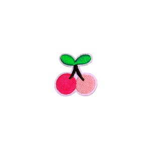 May include: A pink and red embroidered cherry patch with a green stem and leaves.