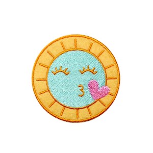 May include: A yellow sun with a blue face and closed eyes, blowing a kiss with a pink heart. The sun has a 3 in the center of the face.