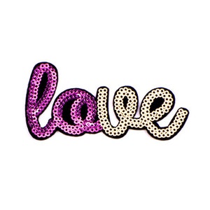 Puede incluir: Un parche de planchado de lentejuelas rosa y blanco que dice "love" en una fuente cursiva.