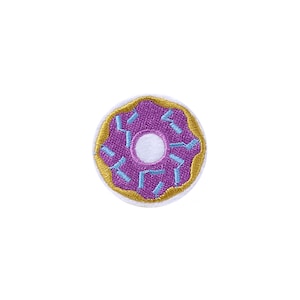 May include: A purple donut with blue sprinkles and a white center, embroidered on a white fabric patch.