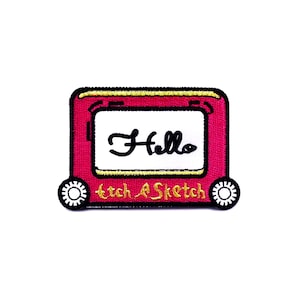 May include: A pink Etch A Sketch patch with the word "Hello" in black script on the screen. The patch has a yellow border and the words "Etch A Sketch" are written in gold at the bottom.
