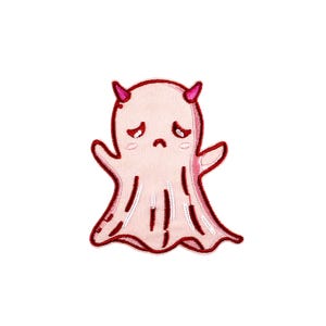 以下が含まれることがあります： 赤い角と悲しい顔をしたピンクの幽霊。幽霊はストライプ模様で刺繍されています。
