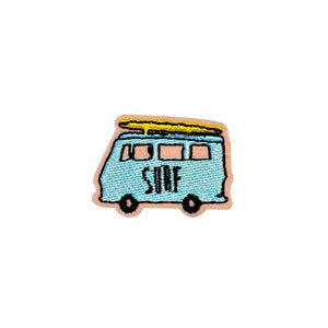 May include: A blue and yellow embroidered patch of a vintage van with a surfboard on the roof. The van has the word "SURF" written on the side.