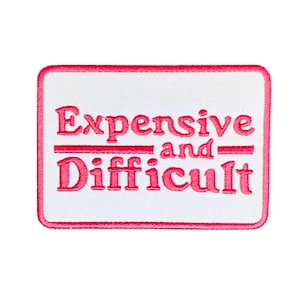 Op de afbeelding: Roze geborduurde patch met een witte achtergrond en de tekst "Expensive and Difficult" in een retro-lettertype.