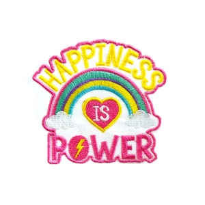 May include: A pink and yellow embroidered patch with a rainbow, a heart with the word "is" inside, and the text "Happiness is Power".
