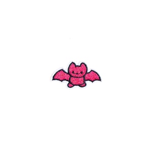May include: A pink embroidered iron-on patch of a cartoon bat with black outlines.