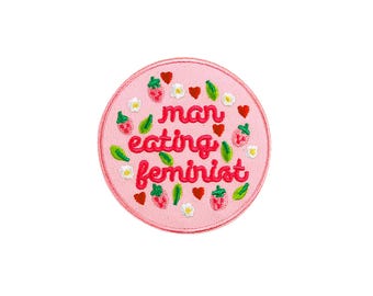 Könnte beinhalten: Runder rosa gestickter Aufnäher mit dem Text "man eating feminist" umgeben von Erdbeeren und Blumen.