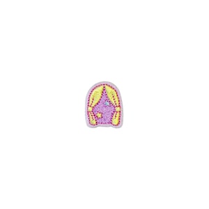 May include: A small, embroidered patch featuring a stylized purple window with yellow curtains. The patch has a light pink border and includes embroidered details in yellow, pink, and blue. The design is whimsical and decorative.