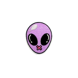 May include: A purple alien patch with large black eyes and a stitched-on red cross over its mouth. The alien has a white highlight on its head and a white border.