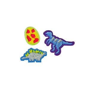 May include: Three embroidered iron-on patches featuring dinosaurs. One patch is a blue dinosaur with purple outlines, another is a gray dinosaur with yellow spines, and the last is a yellow egg with red and white stripes.