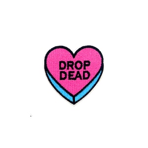 May include: Pink heart-shaped candy patch with blue outline and the text "DROP DEAD" in black.