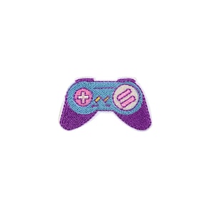 May include: An embroidered patch of a video game controller, featuring a blue and purple design. The controller has pink buttons and a pink and white design.