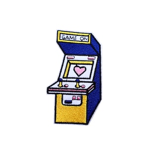 May include: An embroidered iron-on patch of a blue and yellow arcade game with the words "GAME ON" on the top. The game has a pink heart on the screen.