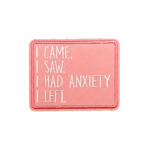 Pode incluir: Etiqueta bordada rosa com o texto "Eu vim, eu vi, eu tive ansiedade, eu fui embora."