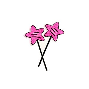 May include: Two pink star-shaped decorations on black sticks, crossed at the bottom.