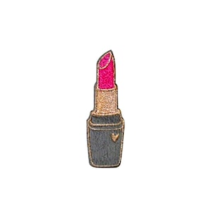 May include: A pink lipstick with a gold band and a black tube. The lipstick has a heart-shaped design on the tube.