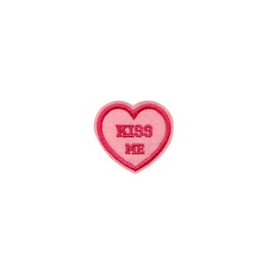 May include: Pink felt heart-shaped patch with a red embroidered outline and the text "KISS ME" in red.