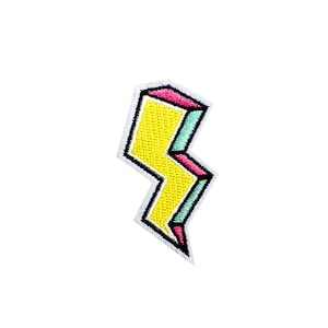 May include: A yellow lightning bolt shaped patch with pink and blue accents. The patch is outlined in black.