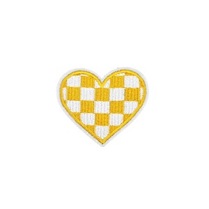 Pode incluir: Um remendo em forma de coração xadrez amarelo e branco. O remendo é contornado com fio branco.