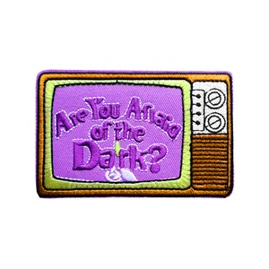 Peut inclure: Patch brodé violet et vert représentant un téléviseur vintage avec le texte "Are You Afraid of the Dark?"