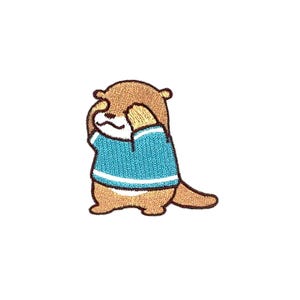May include: An embroidered patch of a brown otter wearing a blue shirt with white stripes, covering its eyes with its paws.