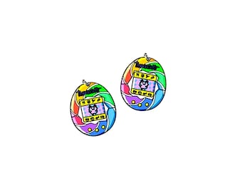 May include: A pair of rainbow-colored digital pet keychains with a black and white pixelated image of a pet on the screen. The keychains are shaped like eggs and have a yellow background with a black outline.