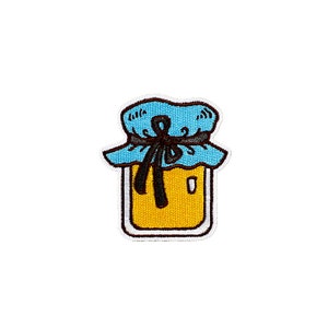 May include: Embroidered patch depicting a cartoon honey jar. The jar is yellow with a white border, and has a blue lid tied with a black bow. This patch is designed for application on clothing or accessories.
